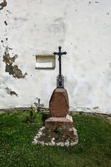 A lonely grave with a tombstone in front of a house wall on a gr
