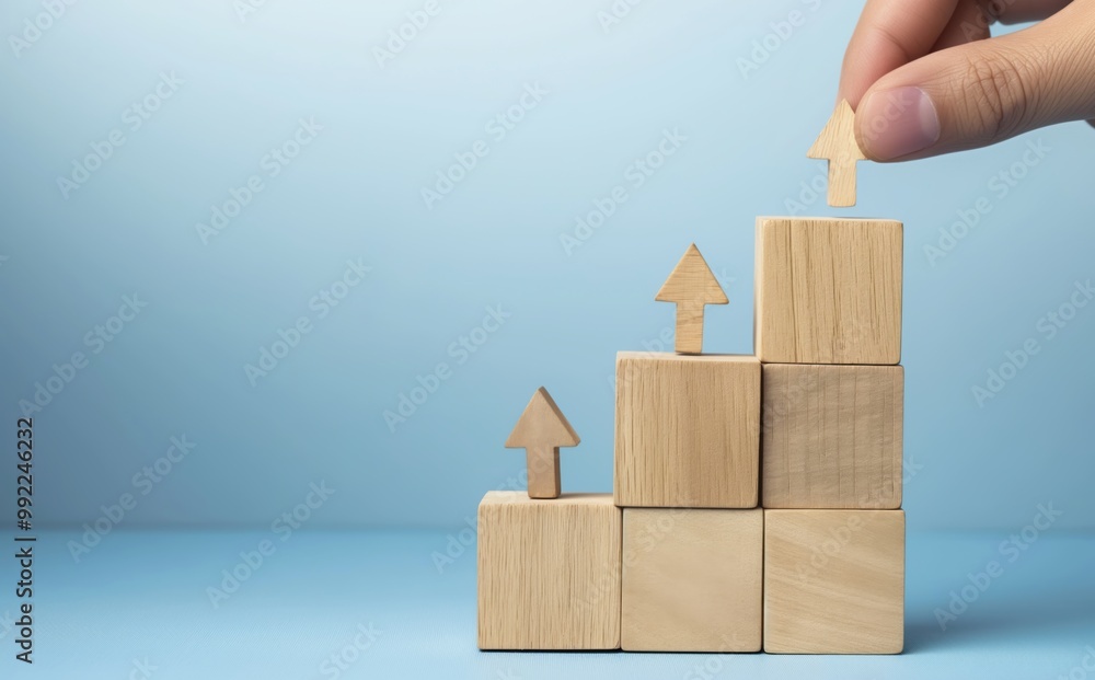 Poster hand is placing a wooden block on top of a wooden block, which is part of a larger stack of wooden b