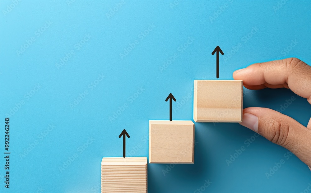 Poster hand is holding three wooden blocks, with one of them having an arrow pointing upwards. the blocks a