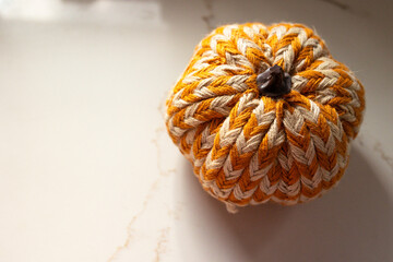 close-up of white and orange striped crafted pumpkin against a marble surface