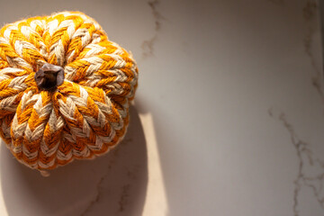 close-up of white and orange striped crafted pumpkin against a marble surface