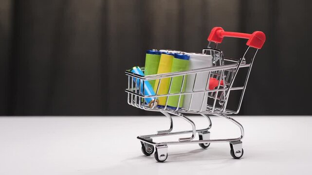 Hand adding battery to shopping cart full of batteries