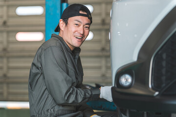 リフトアップした車のタイヤを脱着する整備士の男性
