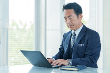 オフィスでパソコンを使う中高年のビジネスマン