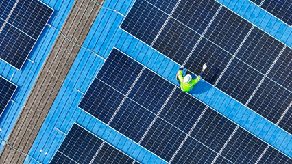 engineer man inspects construction of solar cell panel or photovoltaic cell by electronic device. Industrial Renewable energy of green power. factory worker working on tower roof.