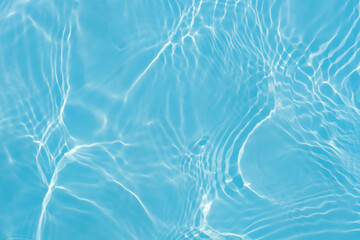 Blue water with ripples on the surface. Defocus blurred transparent blue colored clear calm water surface texture with splashes and bubbles. Water waves with shining pattern texture background.