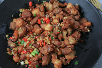 Crispy pork belly cooked with chili and garlic eat with rice on black plate.  Asian local street food style.