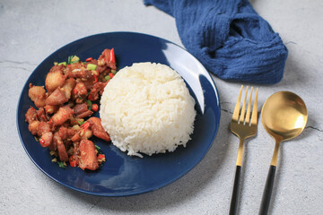 Crispy pork belly cooked with chili and garlic eat with rice on black plate.  Asian local street food style.