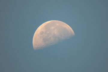 A partial moon hangs in the daylight sky