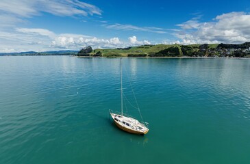 Lone sailing boat moored in calm waters in Maraetai, Auckland, New Zealand.