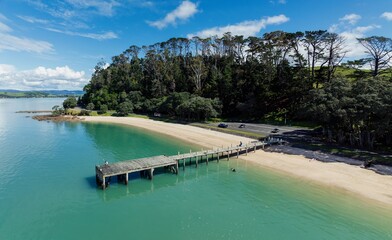 Calm ocean beach and wharf in Maraetai, Auckland, New Zealand.