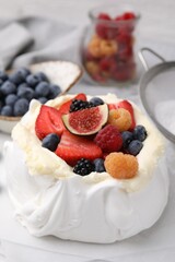 Pavlova cake (meringue dessert) with whipped cream, fresh berries and fig on table, closeup