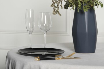 Stylish table setting with black dishware in dining room