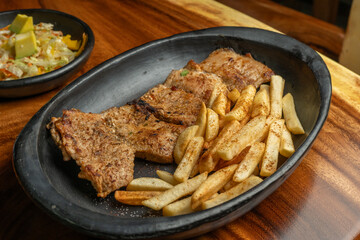 Plato de Lomo de cerdo asado con una porción de papas a la francesa.