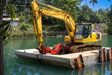 Excavator on a floating platform, cleaning and deepening the river