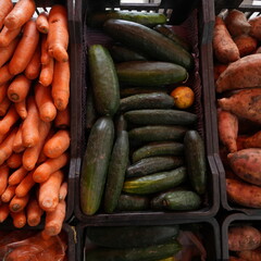 Crates of fresh fruits and vegetables in a traditional grocery store with a variety of healthy and colorful products displayed on wooden shelves