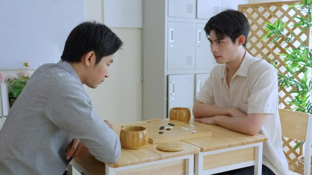 Asian young men playing board game Go during competition in community. 
