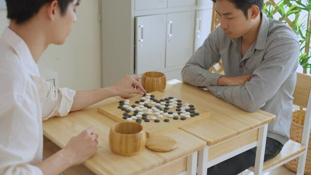 Asian young men playing board game Go during competition in community. 