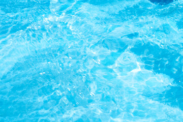 Blue water with ripples on the surface. Defocus blurred transparent blue colored clear calm water surface texture with splashes and bubbles. Water waves with shining pattern texture background.