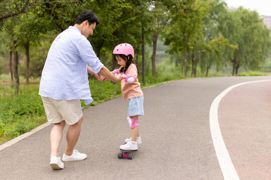 Little Girl Skateboarding With Dad