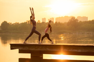 Mom And Daughter Doing Yoga In A Park