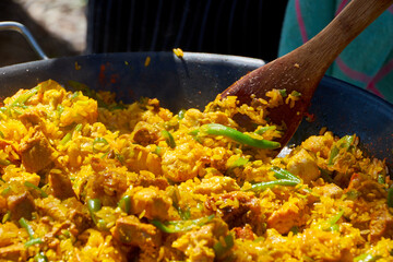 Close up while cooking a paella with vegetables, pork and seafood outdoors