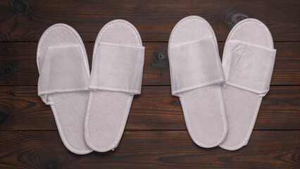 White Disposable Spa Slippers on Wooden Background - Minimalist Hotel Amenities