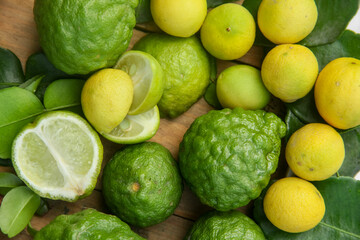 Pile of kaffir limes and limes or Citrus aurantifolia arranged, on leaves background
