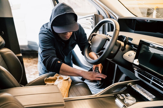 At the car wash, a latin man is vacuuming a sleek and modern car.