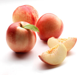 Fresh peaches whole and halved on a white background