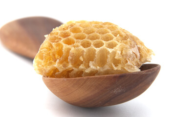 A close-up image of a piece of honeycomb lying on a wooden spoon