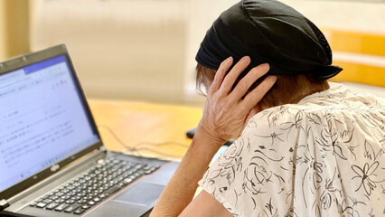 Naklejka premium ノートパソコンの前で耳をふさぐ高齢女性_左から