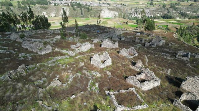 Aerial descends to old stone buildings: Uyo Uyo archeology site, Peru