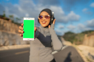hijab woman wearing sportswear holding green screen phone for mockup