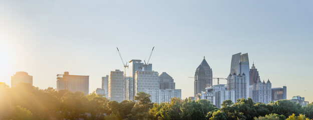 Midtown Atlanta Skyline cityscape showing several prominent buildings and hotels under a clear sky and sun rays.