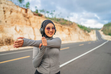 smiling hijab woman stretching before workout, wearing sportswear and glasses, using earphone