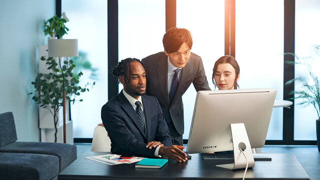 A group of multinational business people having a meeting about corporate management while looking at a computer in an office