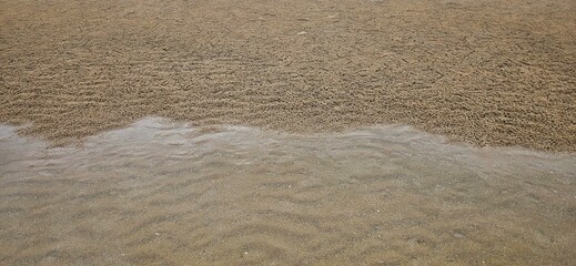 Ocean wave texture on sand beach with sea water background landscape.