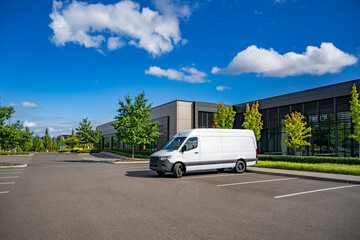 Small business white cargo mini van standing on the parking lot making delivery to commercial...