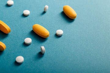 Close-up of white and yellow pills on blue background with copy space.