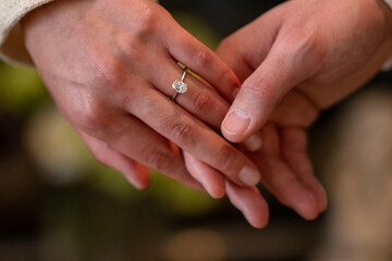 Male holding female hand with a diamond engagement ring. Bride and groom.