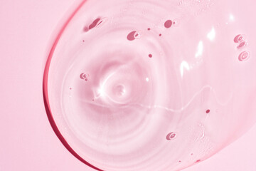 Gel serum texture background. pink skin care liquid swirl. Clear cosmetic cream with bubbles closeup on pink