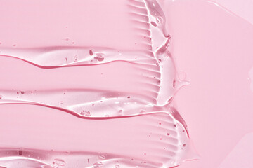 Liquid abstract cosmetic gel smears on pink background. Smear of transparent moisturizing product