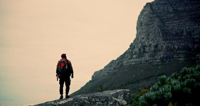 Mountain, hiker and man with backpack, outdoor and sightseeing in nature, hiking and exploring of environment. Location, travel and person in holiday for adventure in Argentina, traveller and trip