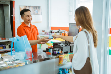 male store cashier serves non-cash payments by female buyers in minimarkets