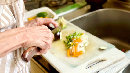 野菜を切る高齢女性の手元 © smile