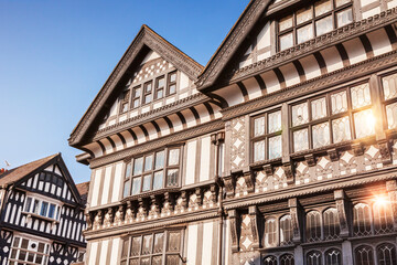 Fototapeta premium Cheshire, England, UK - Black and white buildings in Chester, with beautiful clear blue sky and sunlight reflecting in windows.