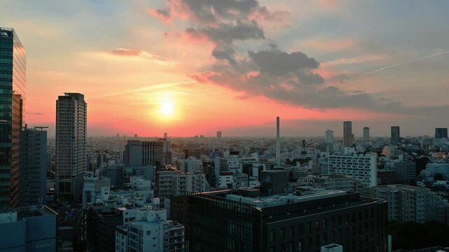 Time lapse of sunset in Tokyo with panoramic view of the setting sun with buildings, skycrapers and houses in the distance.  