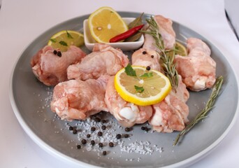 raw chicken wings with pepper and lemon on the plate