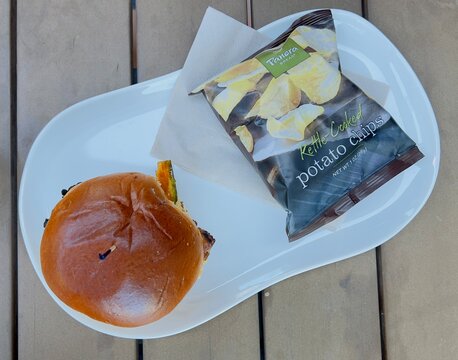 Top-down view of a chicken sandwich from Panera Bread with a bag of potato chips.